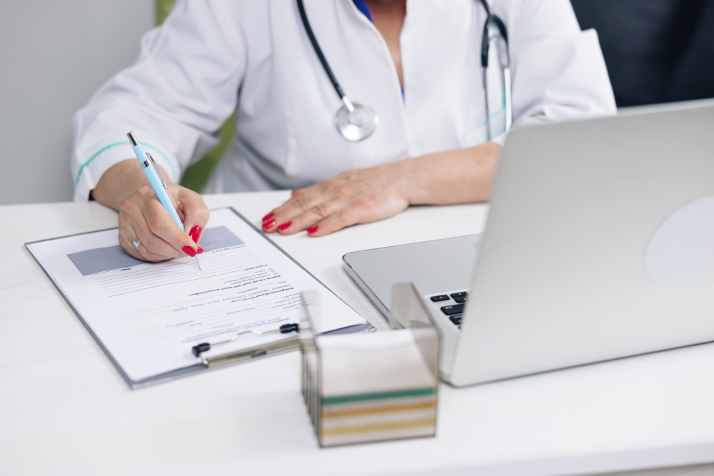 Médico completando una licencia médica junto a un computador portátil — ilustración del proceso de emisión de licencias médicas en Chile.