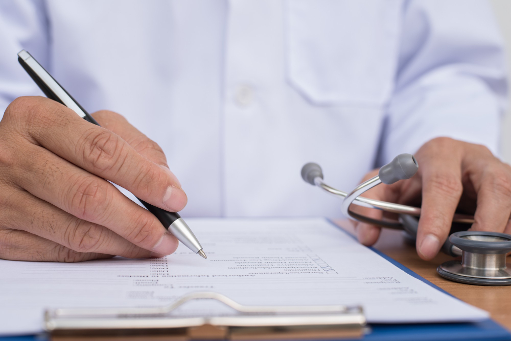 Doctora escribiendo una licencia médica en consulta junto a un computador portátil, ilustración del proceso de licencias en Chile.