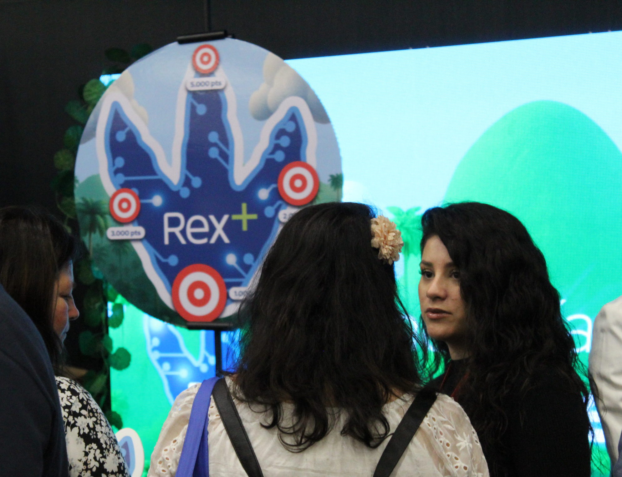 Asistentes conversando frente al stand de Rex+ en el congreso People Experience 2025 en Chile.