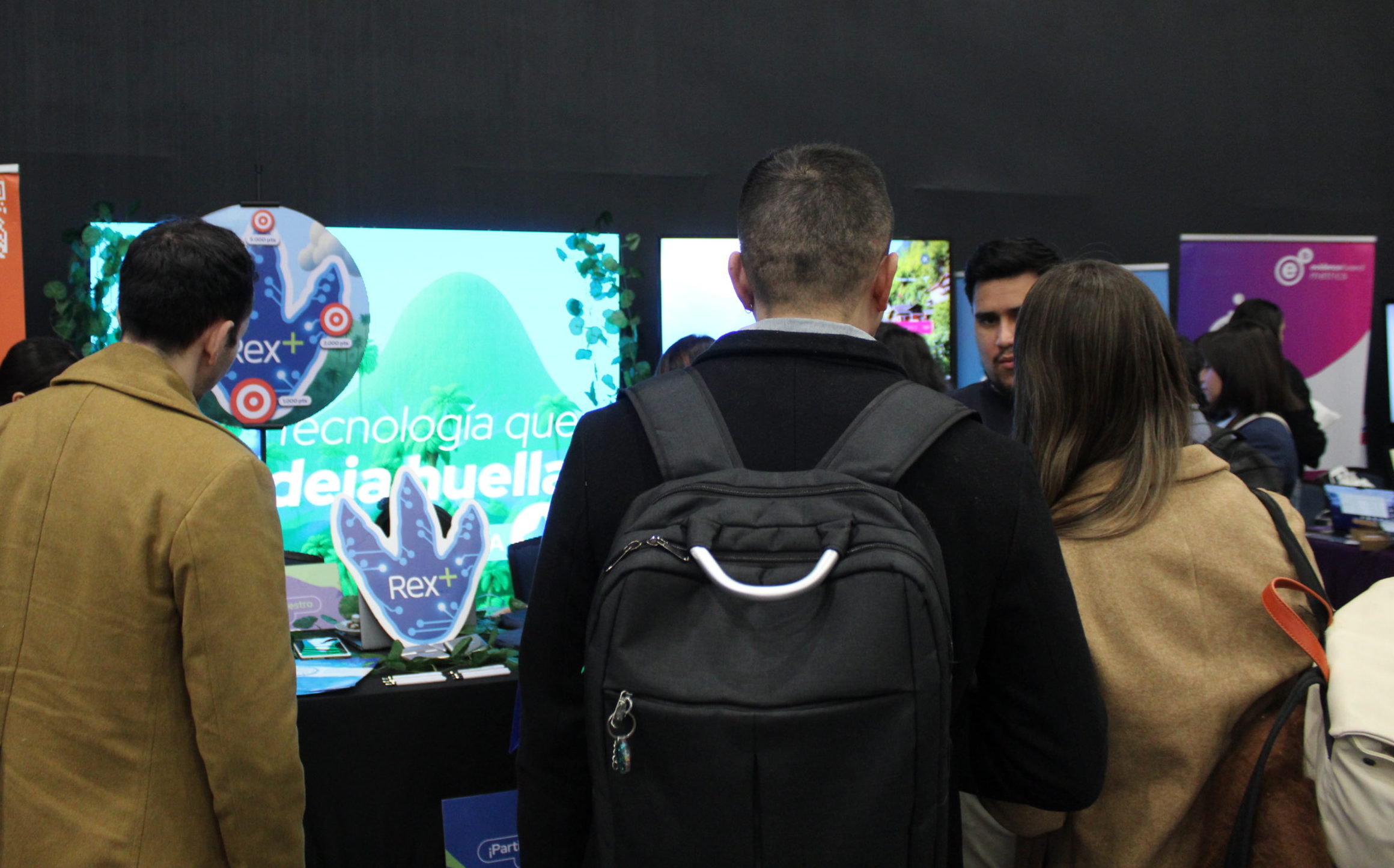 Visitantes observando el stand de Rex+ en el congreso People Experience 2025 en Chile.