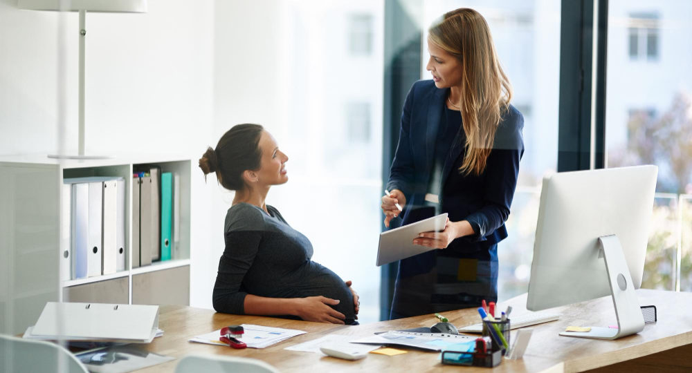 Trabajadora embarazada en oficina aplicando el fuero maternal y paternal según la ley chilena.
